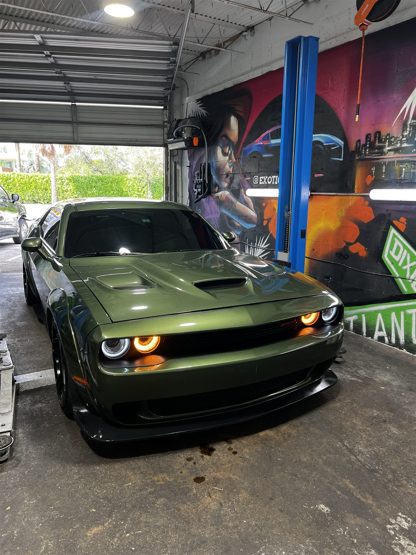Green Dodge Challenger on the lift inside the service bay